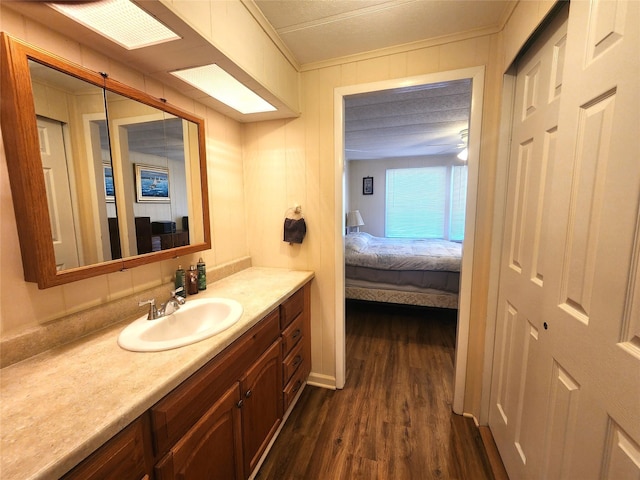 bathroom featuring connected bathroom, ceiling fan, ornamental molding, wood finished floors, and vanity