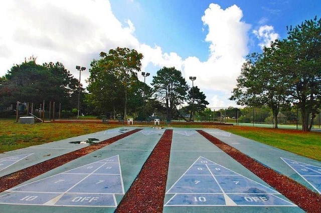 view of property's community featuring fence, shuffleboard, and a yard