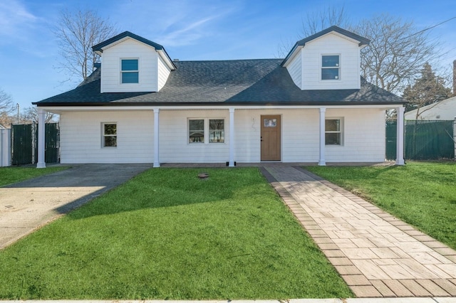 view of front facade featuring a shingled roof, fence, and a front lawn