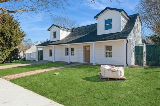 new england style home featuring a front lawn, roof with shingles, and fence