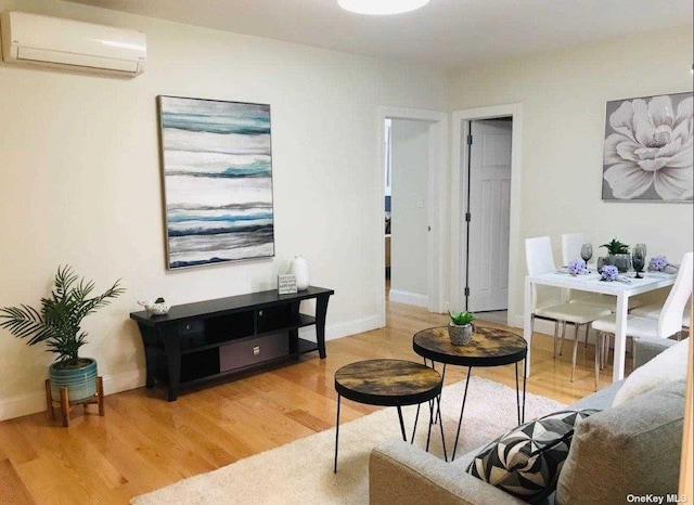 living area featuring light wood-type flooring, baseboards, and a wall mounted AC