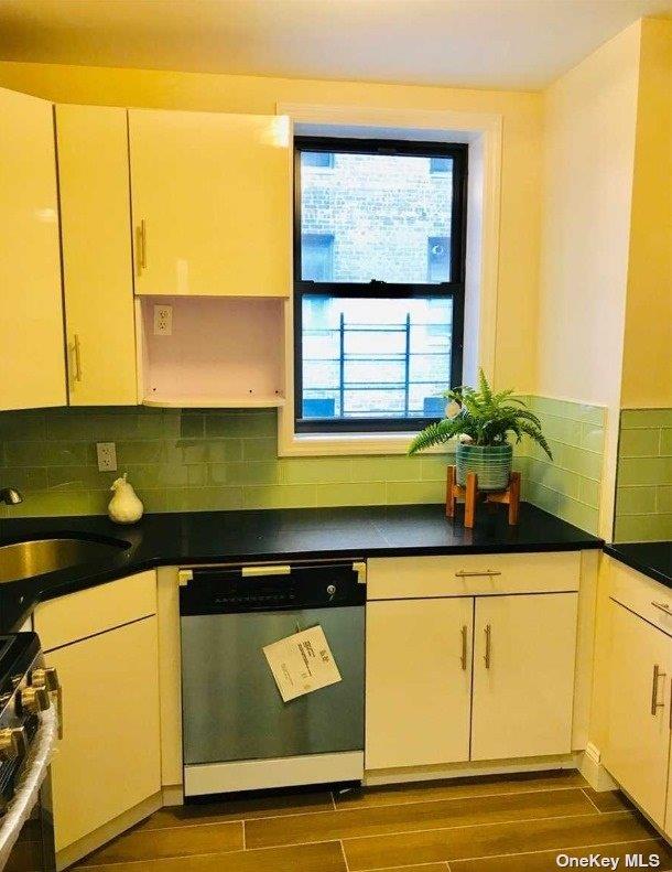 kitchen featuring range, dishwasher, backsplash, wood finish floors, and a sink