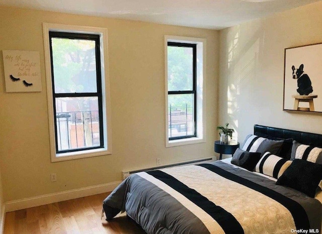 bedroom with baseboards, light wood-style flooring, and baseboard heating