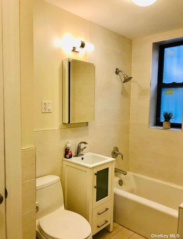 full bath featuring tile walls, shower / bathing tub combination, toilet, vanity, and tile patterned flooring