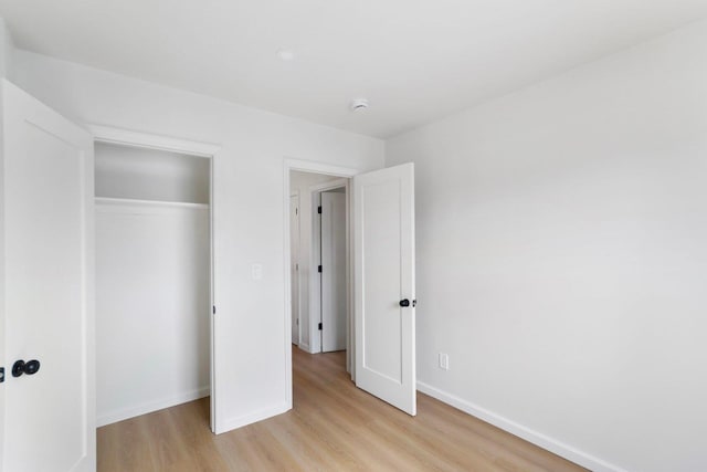 unfurnished bedroom featuring baseboards, a closet, and light wood-style floors