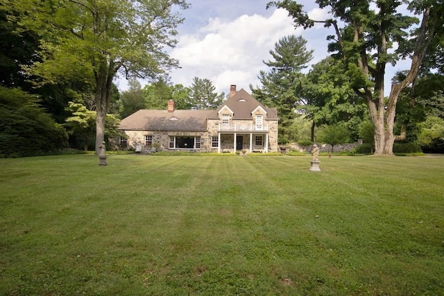 view of front of home with stone siding, a chimney, and a front lawn