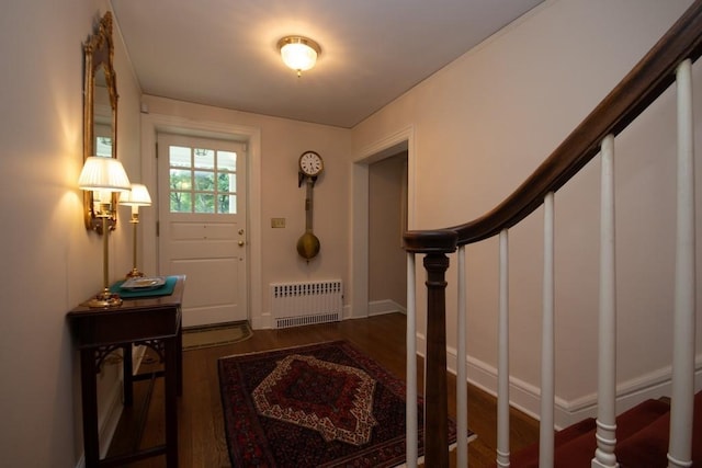 foyer with stairs, baseboards, wood finished floors, and radiator