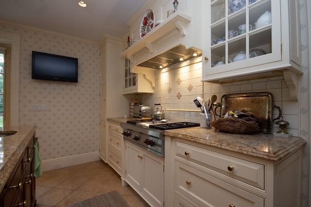 kitchen featuring wallpapered walls, glass insert cabinets, crown molding, stainless steel gas cooktop, and light tile patterned flooring