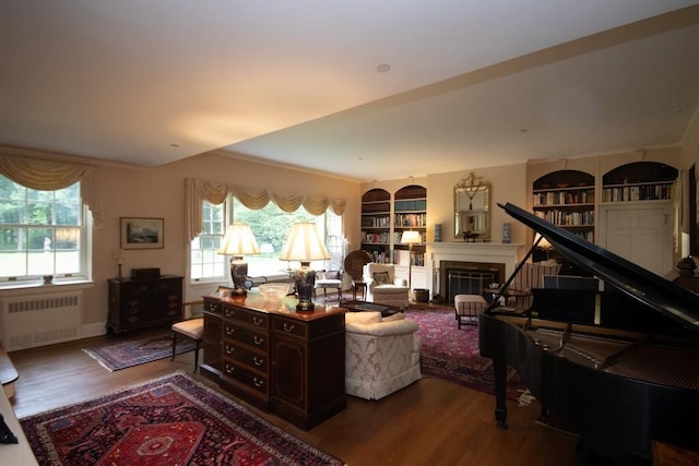 interior space with radiator, a fireplace, built in features, and wood finished floors