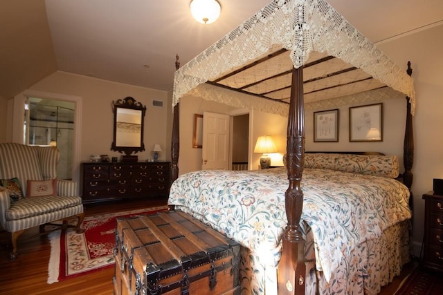 bedroom with visible vents, vaulted ceiling, and wood finished floors