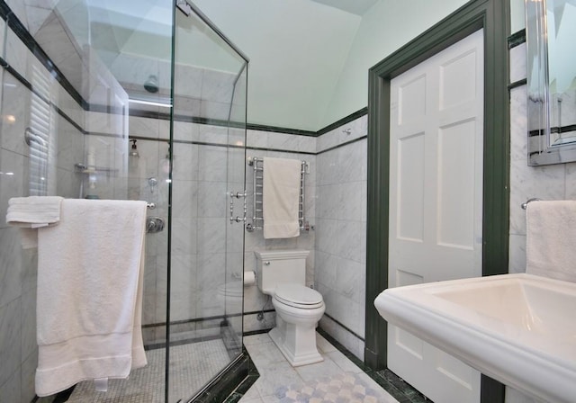 bathroom featuring toilet, a sink, a shower stall, and tile walls