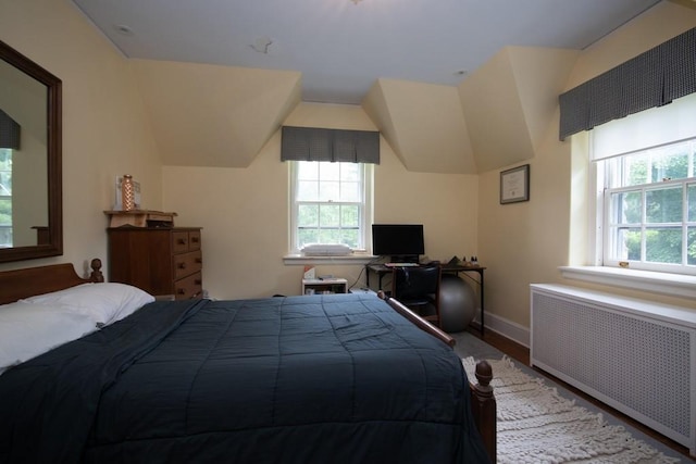 bedroom with lofted ceiling, baseboards, and radiator