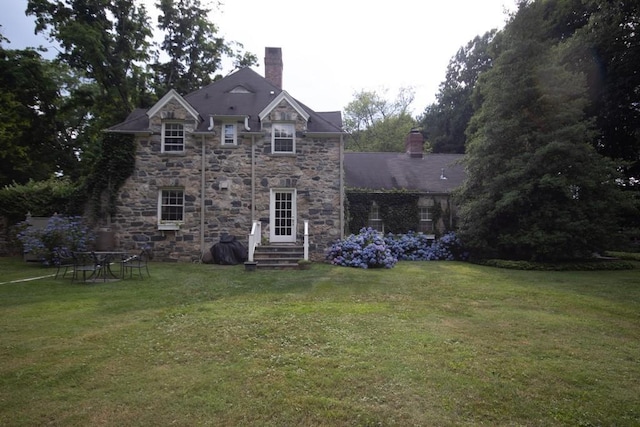 rear view of house featuring a lawn and a chimney