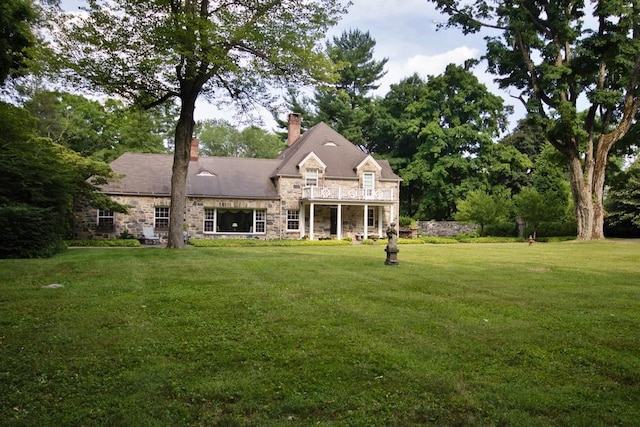 view of front of house featuring stone siding, a front lawn, and a chimney