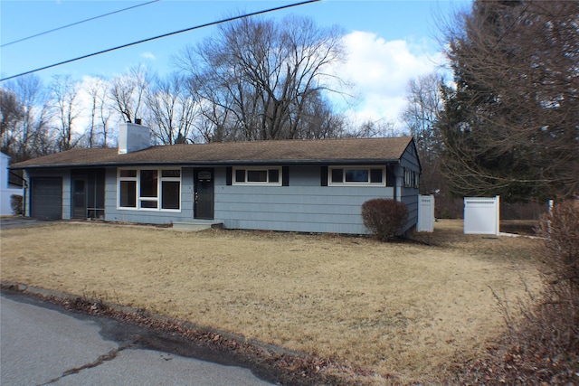 view of front of house with a garage, aphalt driveway, a chimney, and a front yard