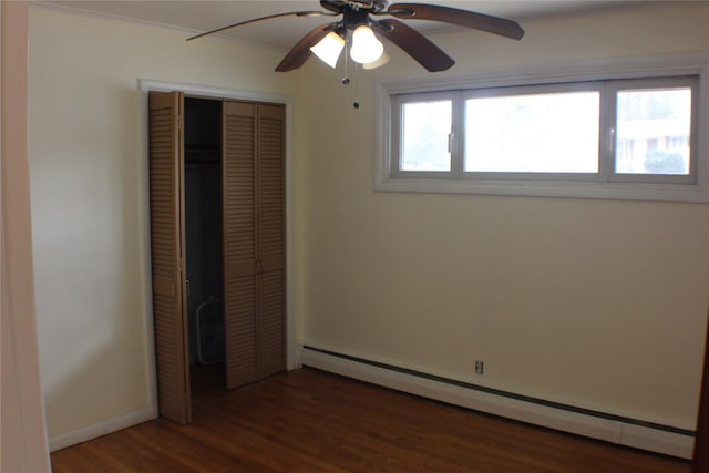 unfurnished bedroom with a baseboard heating unit, ceiling fan, baseboards, wood finished floors, and a closet