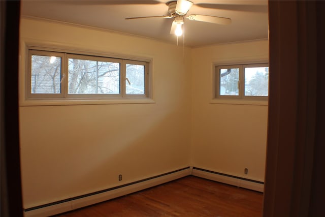 empty room featuring dark wood finished floors, plenty of natural light, baseboard heating, and ornamental molding