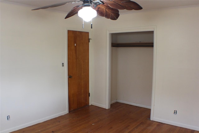 unfurnished bedroom with a closet, crown molding, baseboards, and wood finished floors