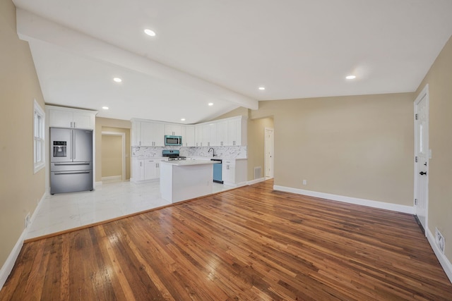 unfurnished living room with light wood-type flooring, lofted ceiling with beams, a sink, recessed lighting, and baseboards