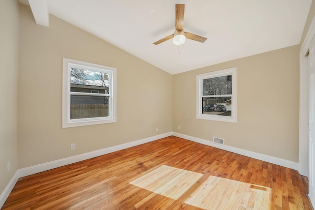 unfurnished room with visible vents, wood finished floors, baseboards, and vaulted ceiling