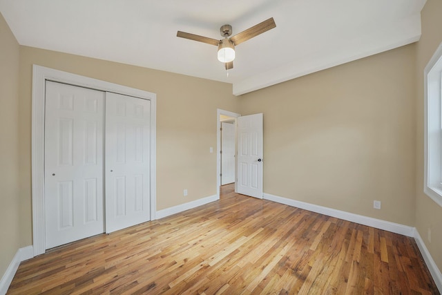 unfurnished bedroom featuring wood-type flooring, a ceiling fan, baseboards, and a closet