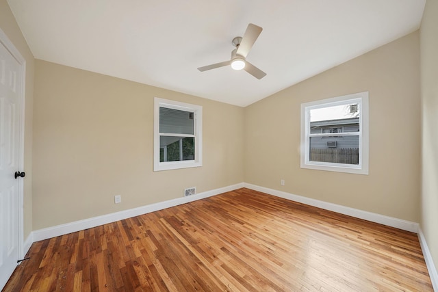 empty room featuring wood finished floors, visible vents, baseboards, lofted ceiling, and ceiling fan