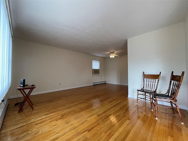 sitting room with baseboards, baseboard heating, ceiling fan, and light wood finished floors