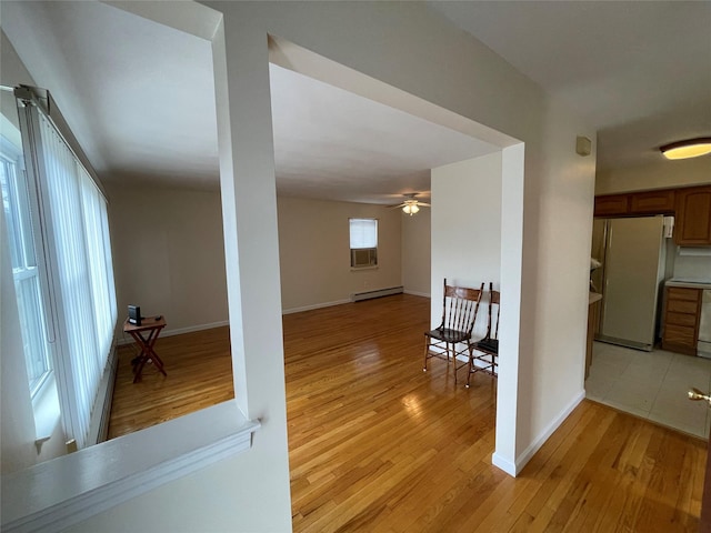 interior space with baseboards, light wood-type flooring, and baseboard heating