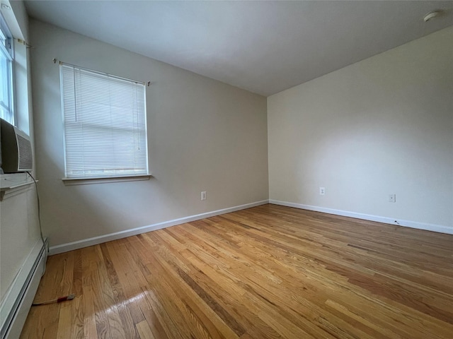 spare room with a baseboard radiator, baseboards, and light wood-style flooring