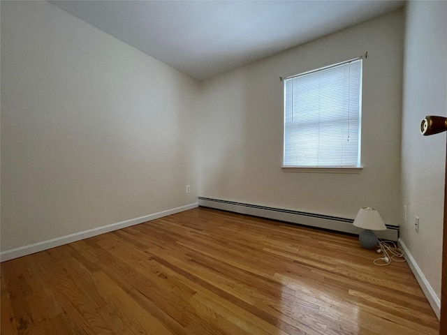 spare room with a baseboard radiator, baseboards, and light wood-style floors