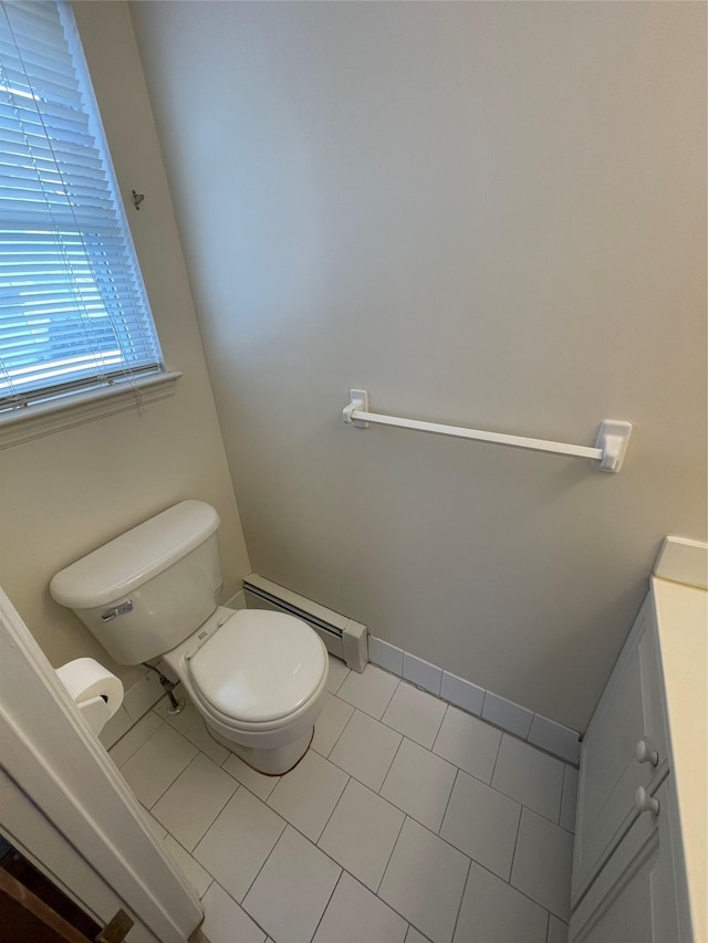 half bath featuring tile patterned flooring, toilet, a baseboard heating unit, and baseboards