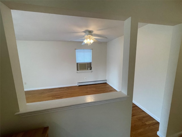 empty room featuring wood finished floors, cooling unit, baseboards, baseboard heating, and ceiling fan