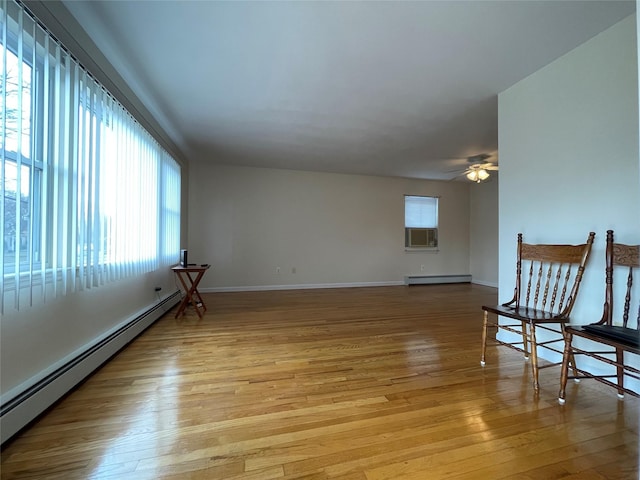 unfurnished room with baseboards, baseboard heating, ceiling fan, and light wood finished floors