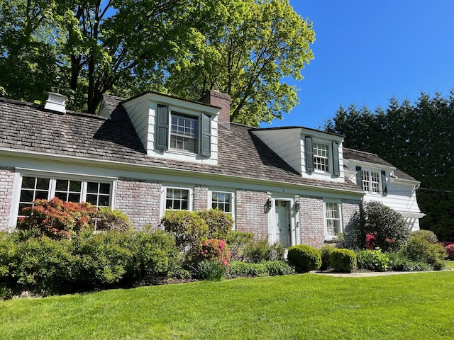 cape cod home with a chimney and a front yard