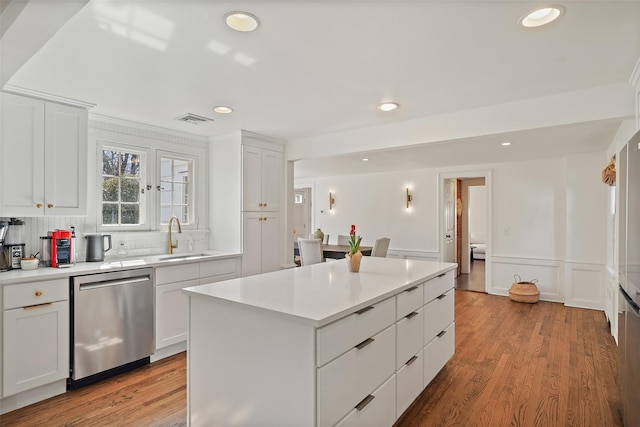 kitchen featuring visible vents, light wood-type flooring, a sink, stainless steel dishwasher, and white cabinets