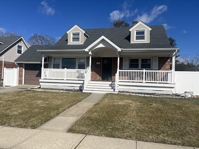 cape cod house featuring covered porch, a shingled roof, a front lawn, and brick siding