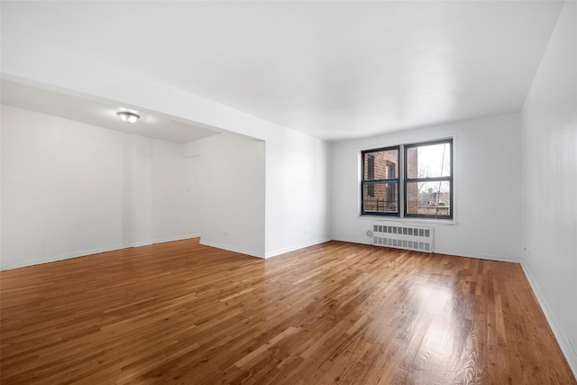 empty room with radiator, baseboards, and hardwood / wood-style floors