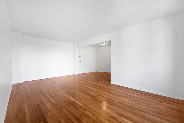 spare room with baseboards and hardwood / wood-style flooring