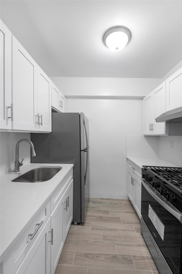 kitchen with white cabinets, range with gas stovetop, a sink, and light countertops