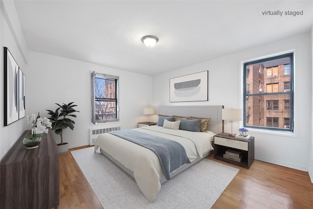 bedroom featuring multiple windows, wood finished floors, and radiator