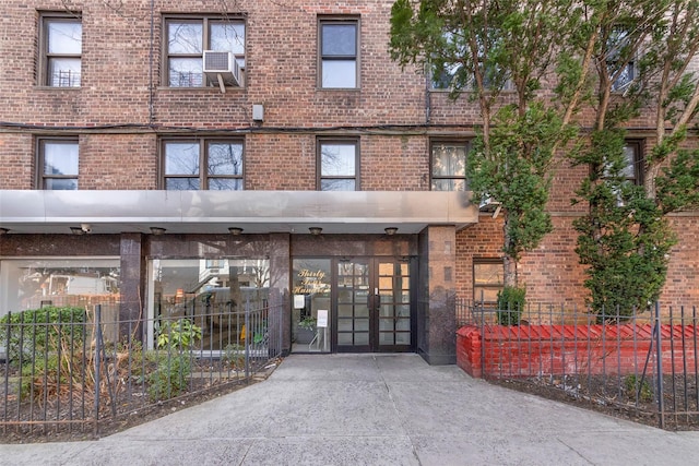 entrance to property with fence, french doors, and brick siding