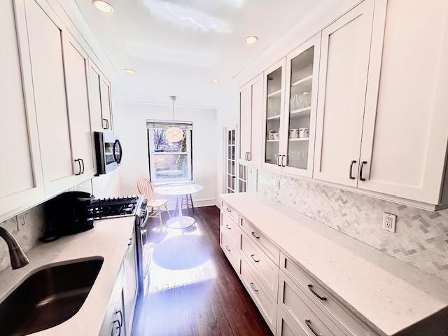 kitchen with stainless steel appliances, dark wood finished floors, white cabinetry, and a sink