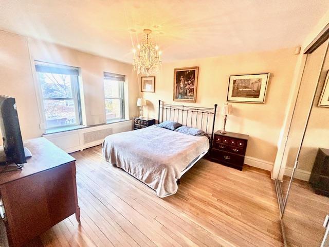 bedroom featuring light wood-style floors, baseboards, and an inviting chandelier