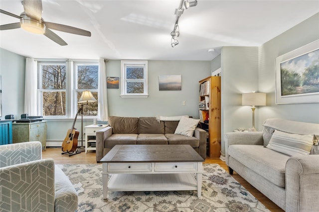 living area with track lighting, baseboard heating, wood finished floors, and a ceiling fan