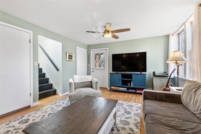 living area featuring stairway, wood finished floors, baseboards, and ceiling fan