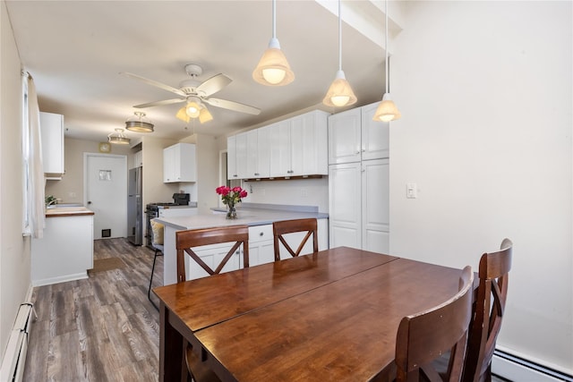 dining area featuring baseboard heating, dark wood-style flooring, and a ceiling fan