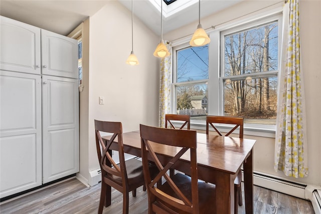 dining room with light wood-style floors, baseboard heating, and a skylight