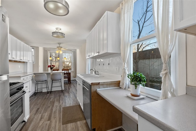 kitchen with decorative backsplash, white cabinetry, stainless steel appliances, and a sink