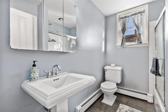 bathroom with a sink, a shower with door, baseboard heating, and toilet