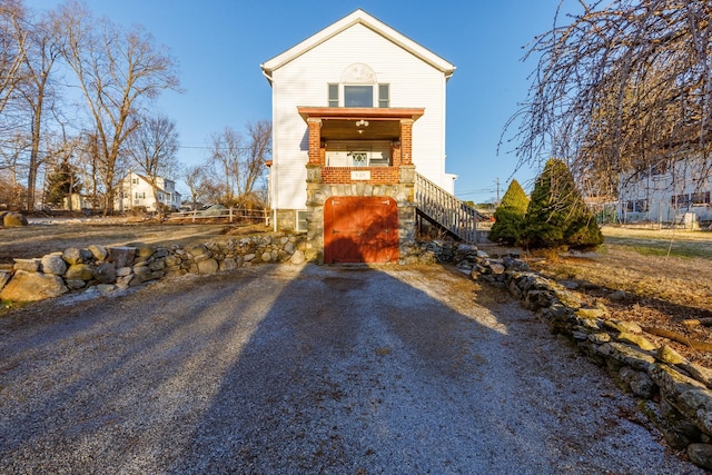 view of front of property featuring gravel driveway and stairs